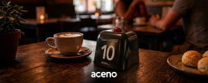 botao chama garcom em mesa de padaria ao lado uma xicara de capuccino e pao de queijo